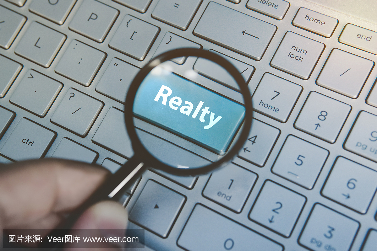 放大藍色按鈕Realty通過放大鏡查看鍵盤背景。互聯網財產搜索服務的概念。在網上尋找地產代理信息。電腦搜索房地產經紀人。
